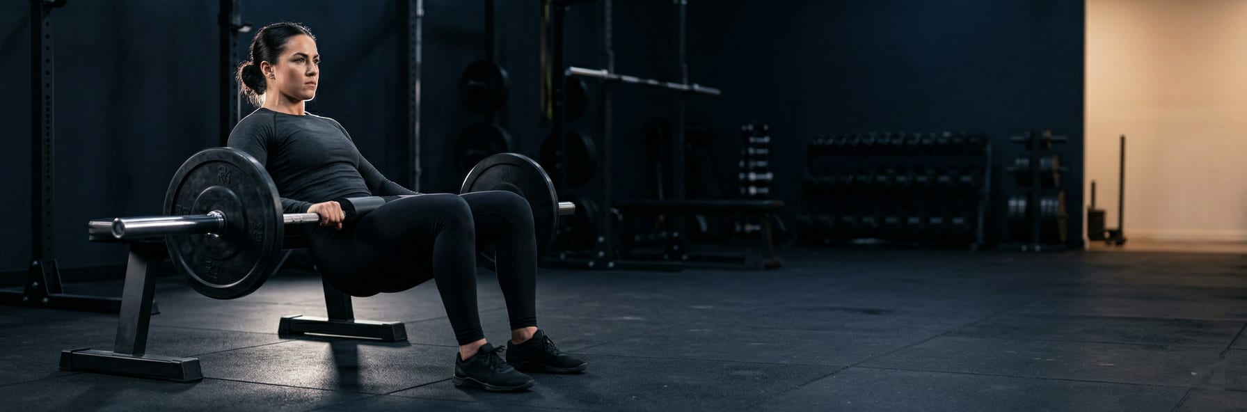 Woman performing barbell hip thrusts in a gym setting